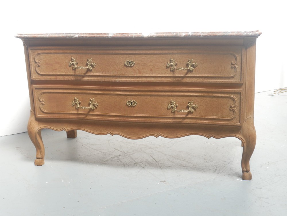 A French provincial style oak chest of drawers featuring two moulded panel drawers, ornate cast brass handles, cabriole legs, and a red-toned marble top. View VI