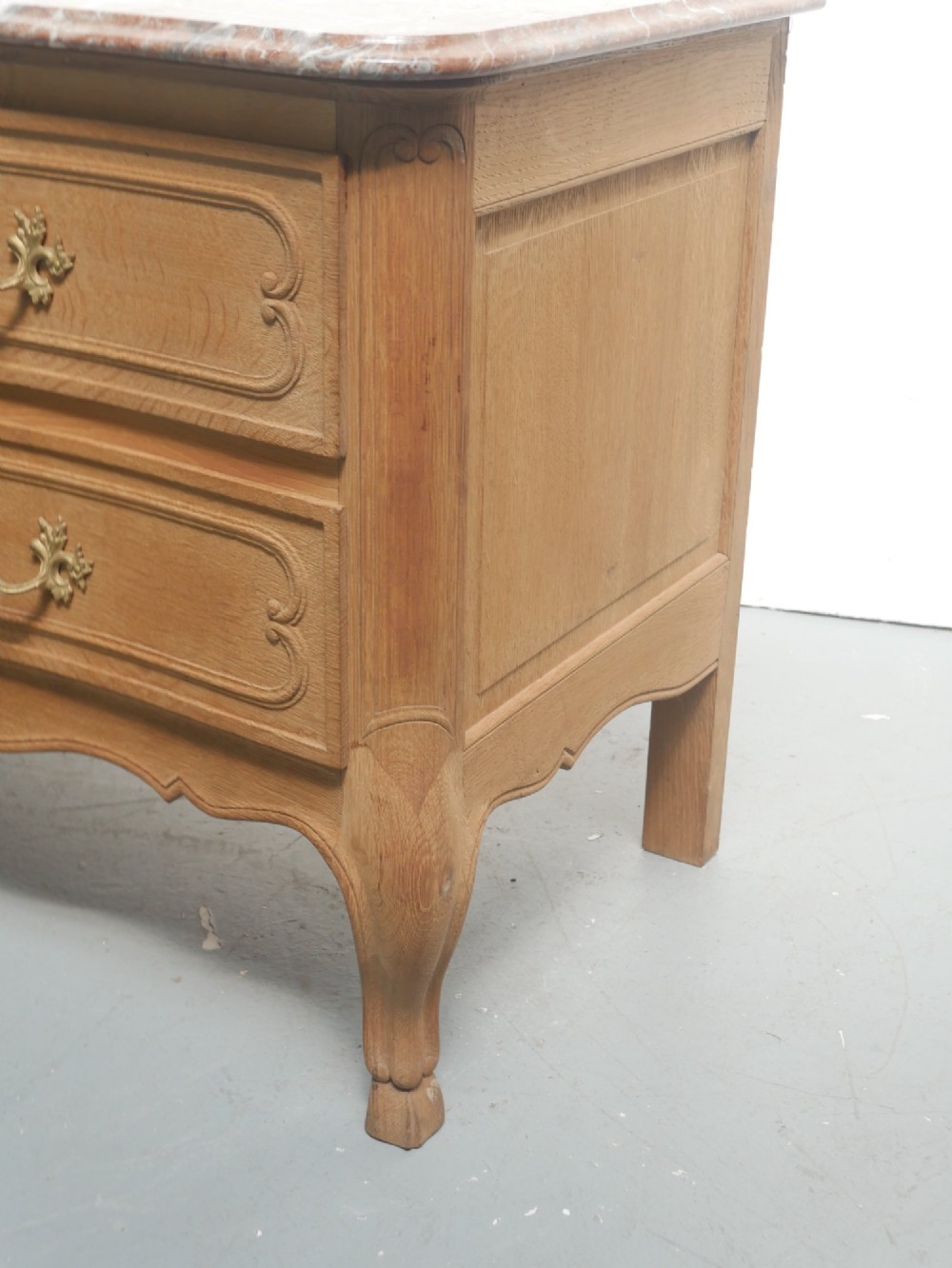 A French provincial style oak chest of drawers featuring two moulded panel drawers, ornate cast brass handles, cabriole legs, and a red-toned marble top. View VII