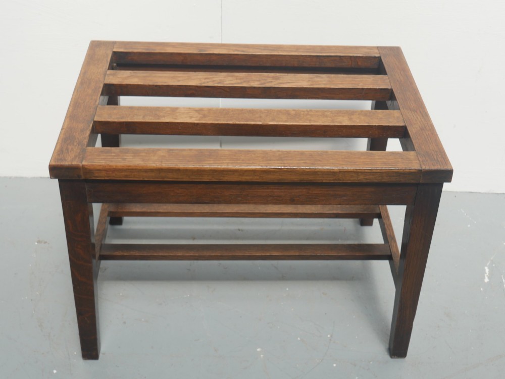 A solid dark oak luggage rack featuring four square legs, supportive stretchers, and a slatted top surface. View III