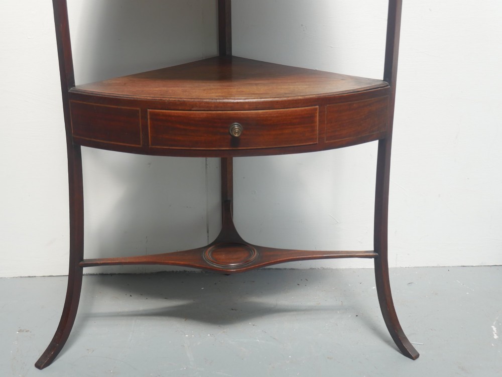 A Georgian mahogany corner washstand featuring a high curved splashback, circular cutouts with a fitted ceramic basin, a middle drawer tier, and splayed legs. View II