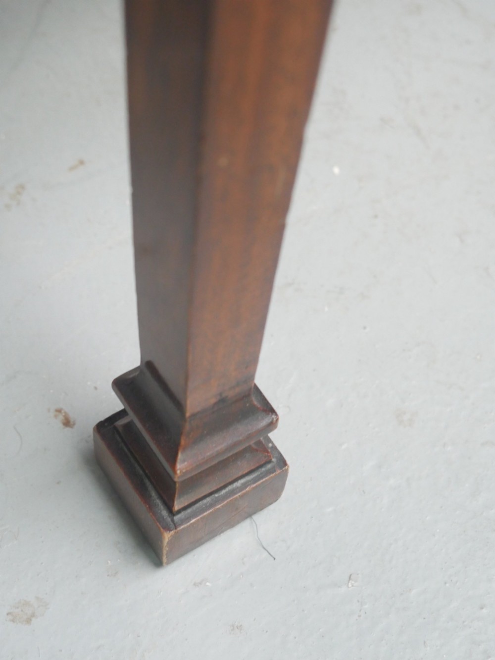 A mahogany console table featuring a shaped top, a lower tier shelf, and tapered square legs. View VI