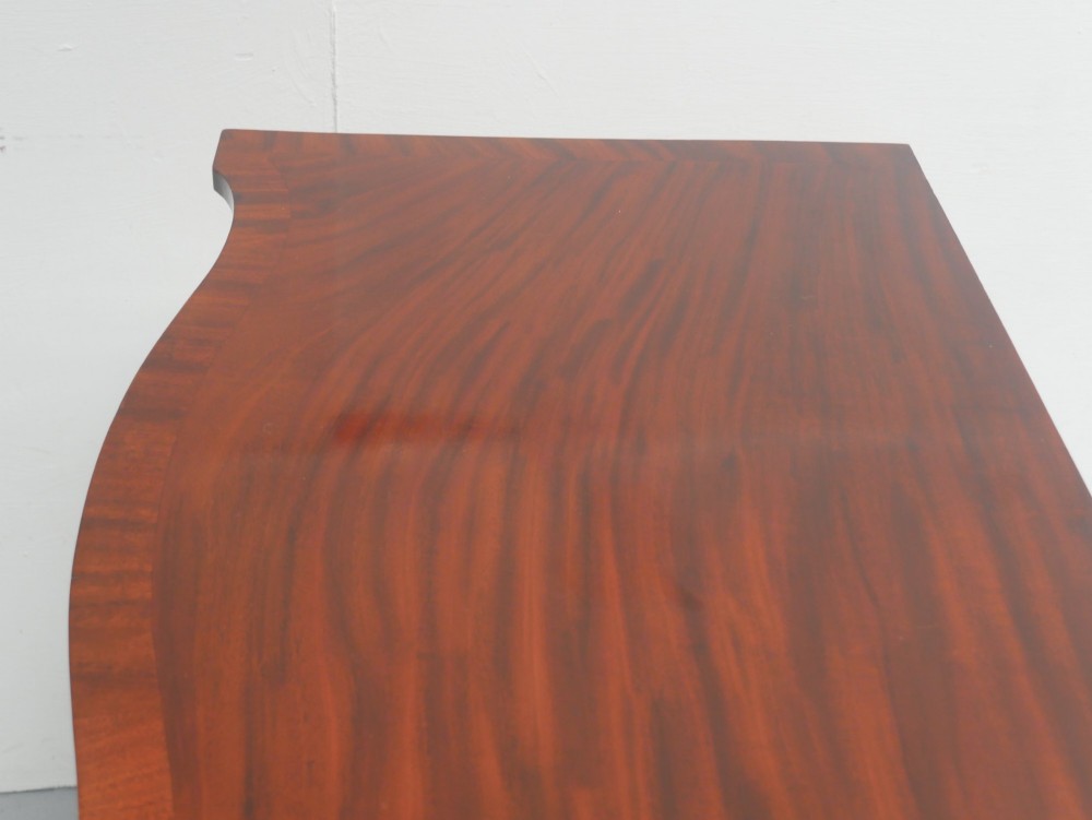 A mahogany console table featuring a shaped top, a lower tier shelf, and tapered square legs. View VII