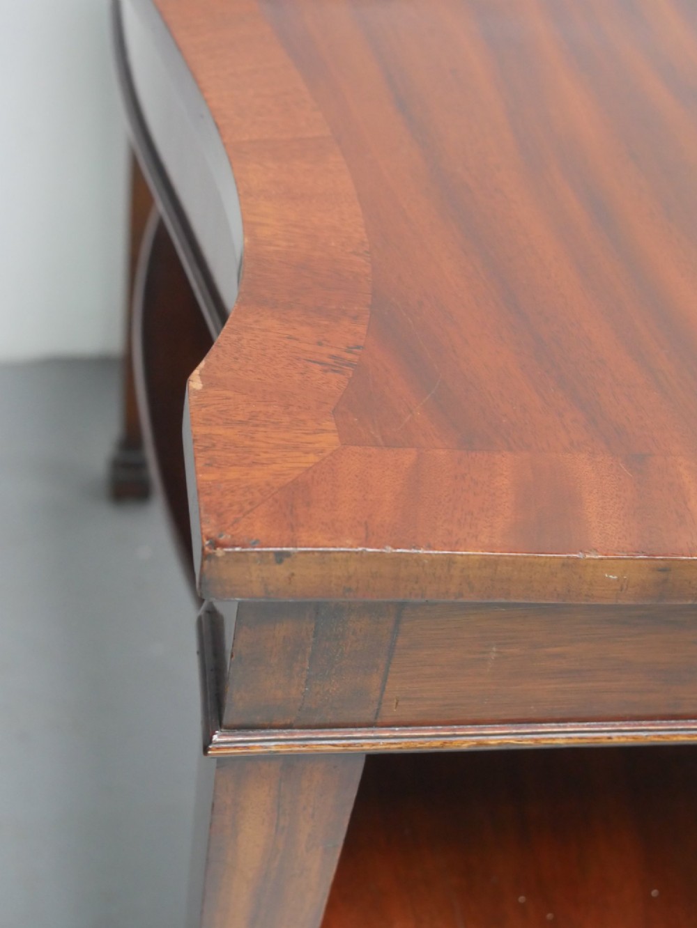A mahogany console table featuring a shaped top, a lower tier shelf, and tapered square legs. View IX