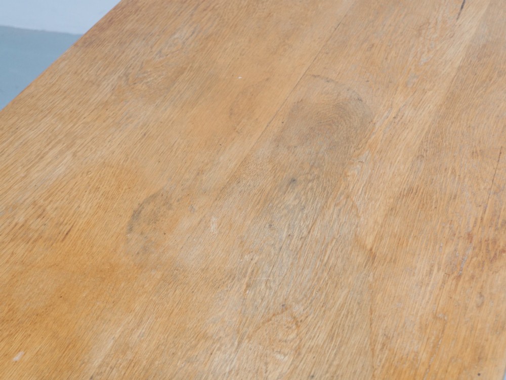 A solid warm brown oak refectory dining table featuring a rectangular plank top, flat trestle leg supports, and a low central stretcher. View VI