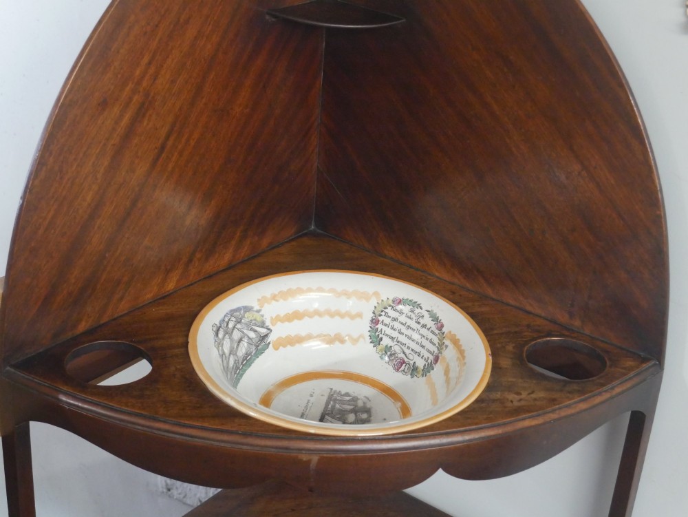 A Georgian mahogany corner washstand featuring a high curved splashback, circular cutouts with a fitted ceramic basin, a middle drawer tier, and splayed legs. View VIII