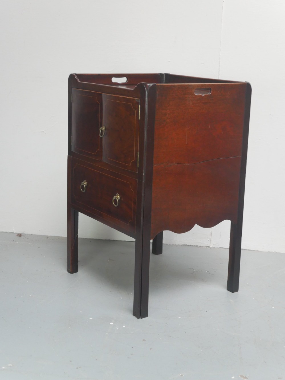 A Georgian mahogany bedside cabinet with a tray top gallery, double inlaid cupboard doors, a lower drawer, and square legs. View V