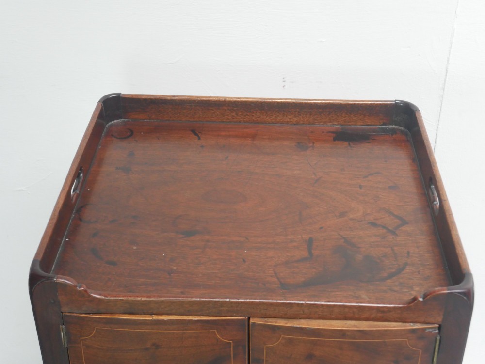 A Georgian mahogany bedside cabinet with a tray top gallery, double inlaid cupboard doors, a lower drawer, and square legs. View VII