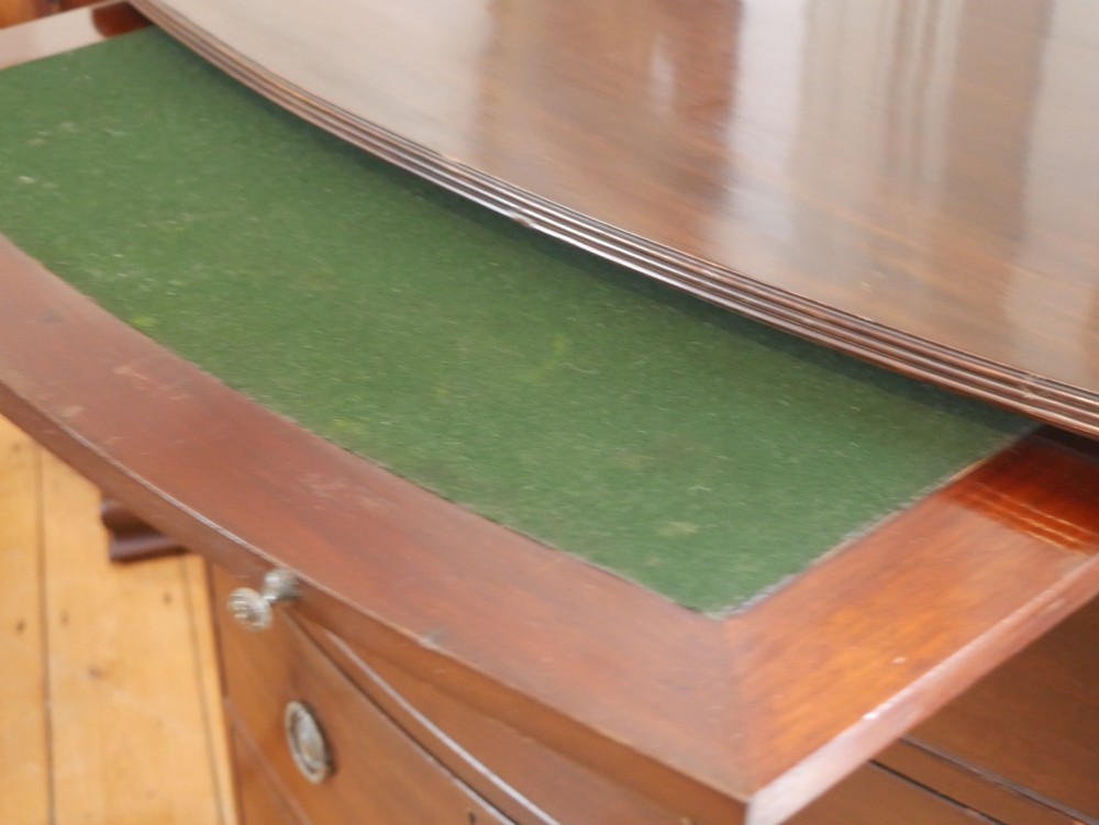 An antique dark mahogany bowfront chest of drawers featuring four graduated drawers with brass ring handles and splayed bracket feet. View VII