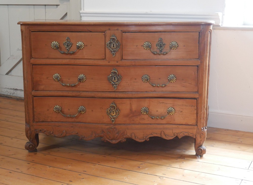 An eighteenth-century French provincial walnut commode featuring three drawers with brass handles, a carved apron, and short cabriole legs. View II