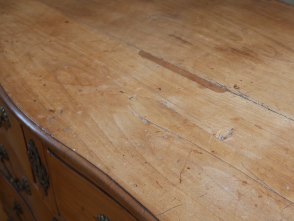 An eighteenth-century French provincial walnut commode featuring three drawers with brass handles, a carved apron, and short cabriole legs. View VI