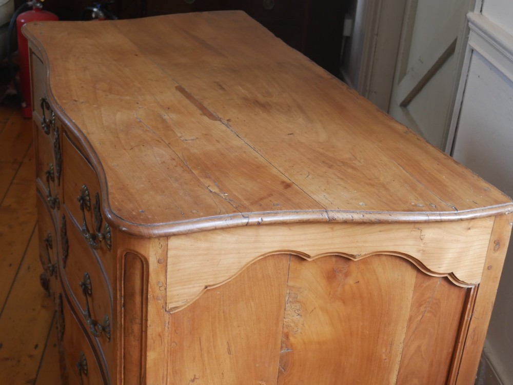 An eighteenth-century French provincial walnut commode featuring three drawers with brass handles, a carved apron, and short cabriole legs. View VII