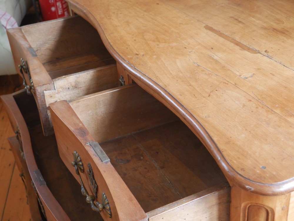 An eighteenth-century French provincial walnut commode featuring three drawers with brass handles, a carved apron, and short cabriole legs. View X