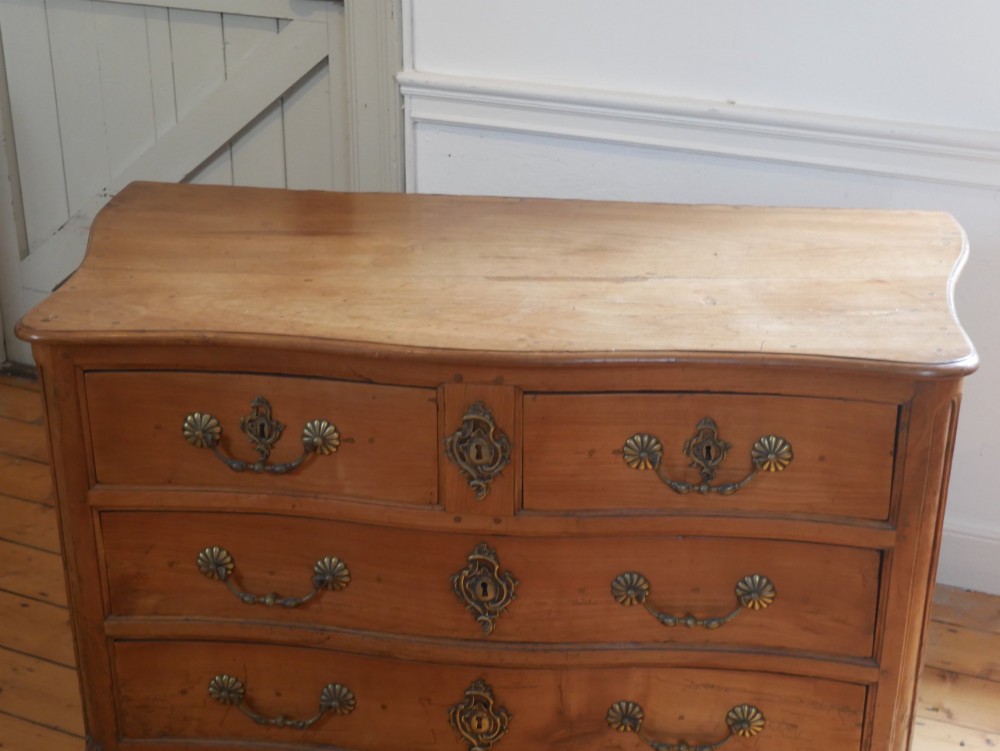 An eighteenth-century French provincial walnut commode featuring three drawers with brass handles, a carved apron, and short cabriole legs. View XII