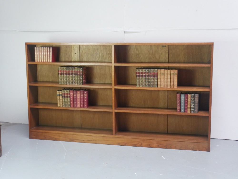 A wide, low Arts and Crafts oak bookcase featuring double open bays with multiple horizontal shelves.
