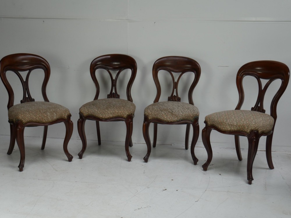A set of four 19th-century mahogany dining chairs with carved open backs, upholstered seats, and cabriole legs.