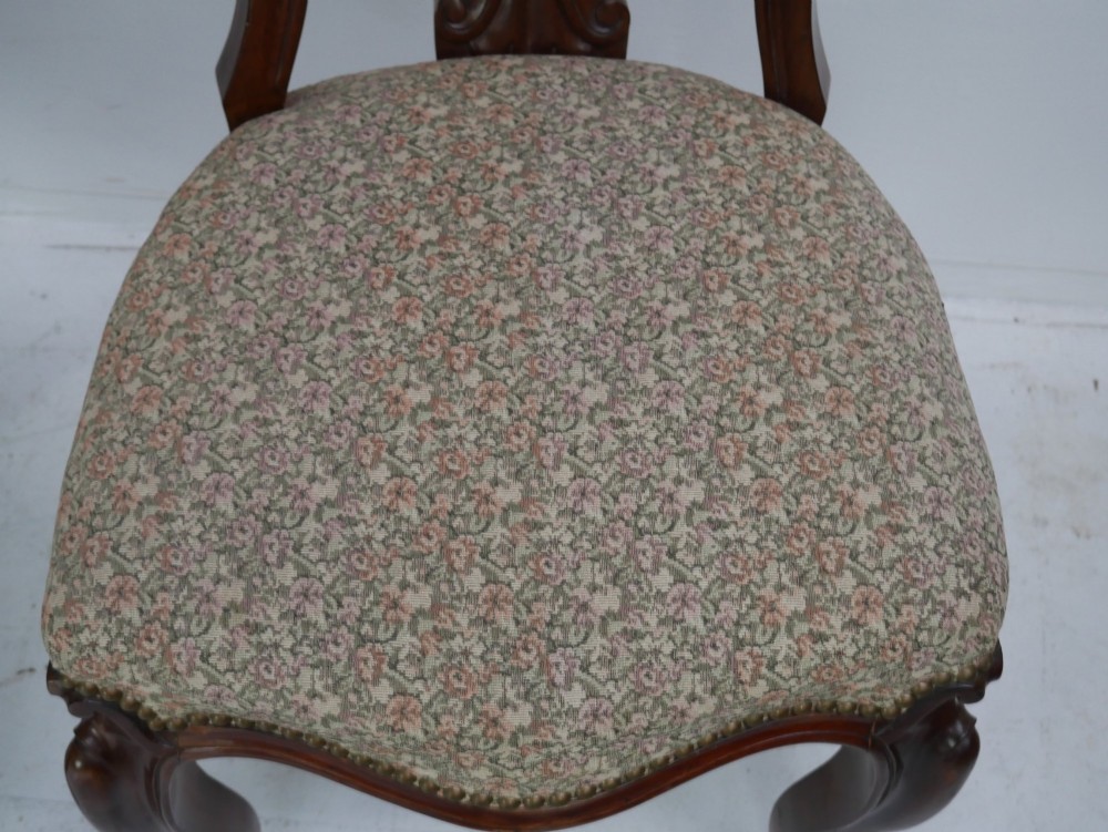 A set of four 19th-century mahogany dining chairs with carved open backs, upholstered seats, and cabriole legs. View VI