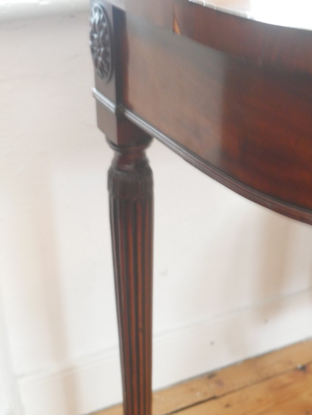 An English 19th-century demilune console table with hand-painted floral swags across the curved apron and slender tapered square legs. View II