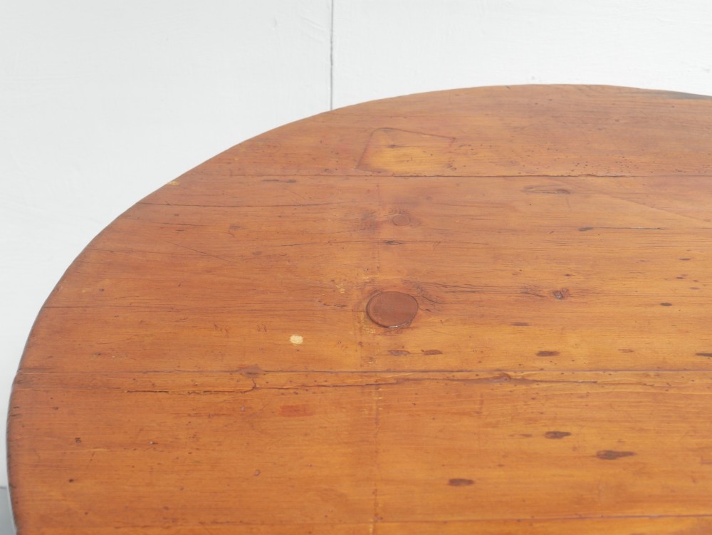A circular pine cricket table featuring three turned legs joined by a deep triangular apron in a warm brown timber finish. View IV