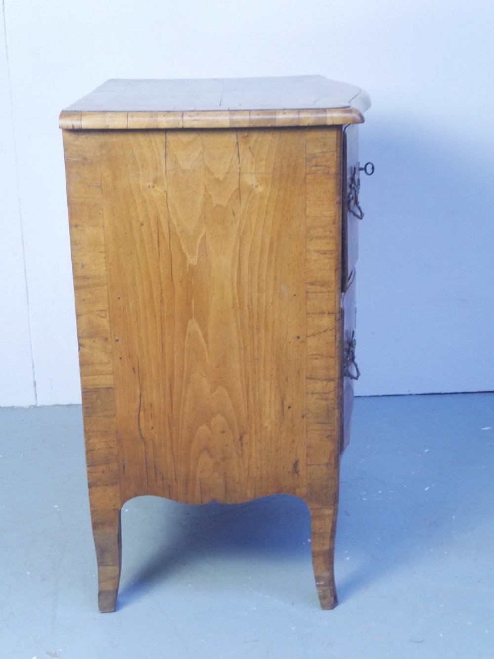 An 18th-century Swedish wooden commode featuring two bow-fronted drawers, ornamental brass handles, escutcheons, and curved lower legs. View V