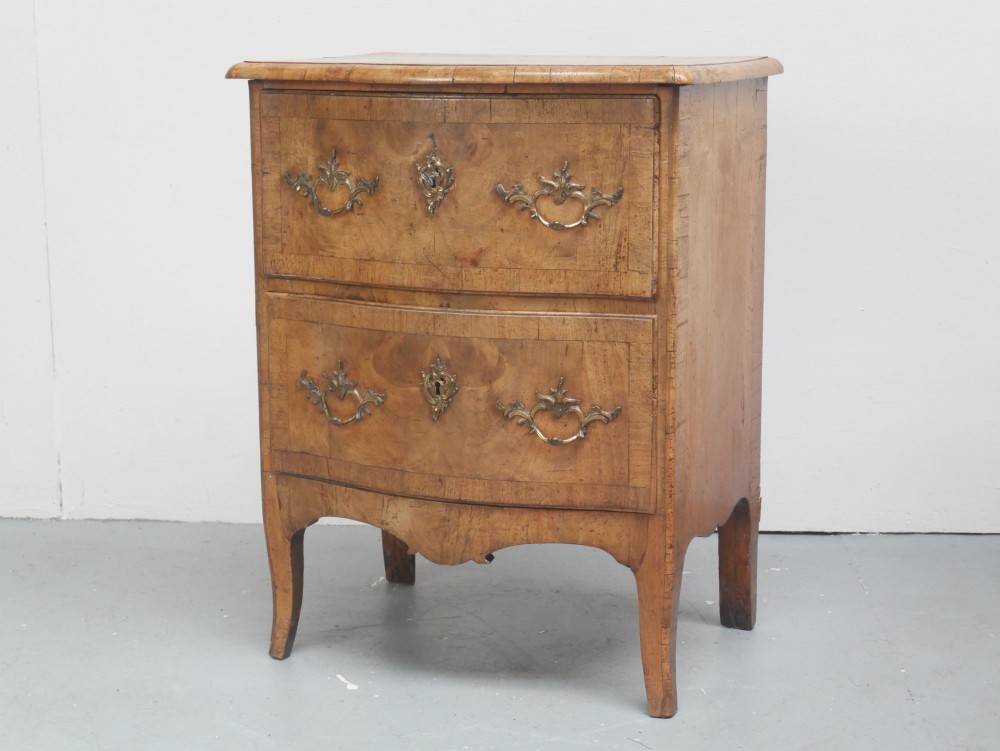 An 18th-century Swedish wooden commode featuring two bow-fronted drawers, ornamental brass handles, escutcheons, and curved lower legs.