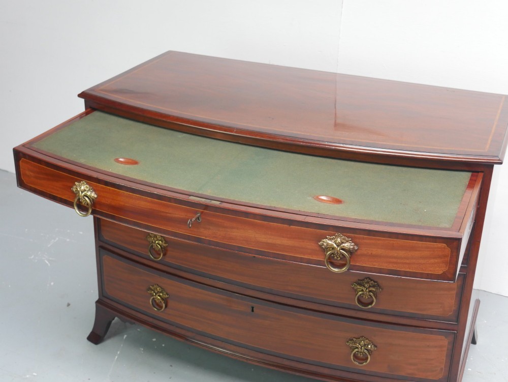 A Georgian flame mahogany bowfront chest of drawers featuring four graduating drawers with brass ring handles and bracket feet. View II