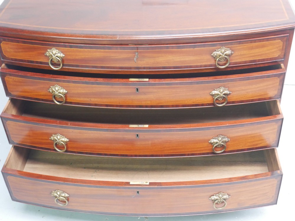 A Georgian flame mahogany bowfront chest of drawers featuring four graduating drawers with brass ring handles and bracket feet. View V