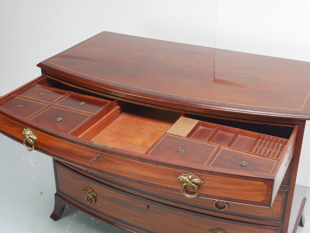 A Georgian flame mahogany bowfront chest of drawers featuring four graduating drawers with brass ring handles and bracket feet. View VII