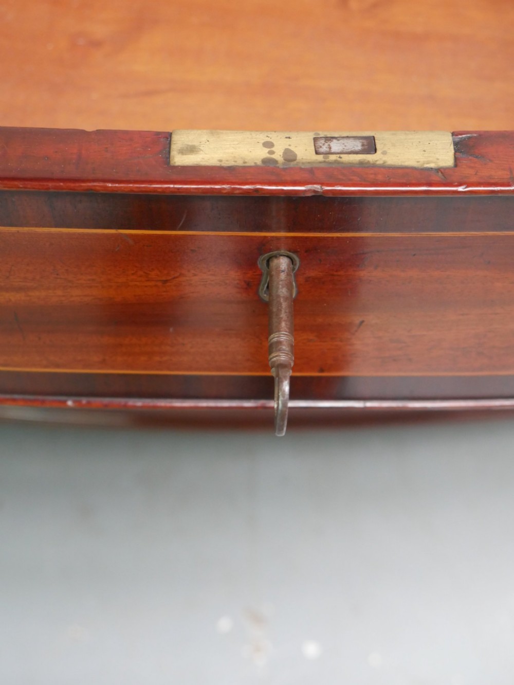 A Georgian flame mahogany bowfront chest of drawers featuring four graduating drawers with brass ring handles and bracket feet. View X