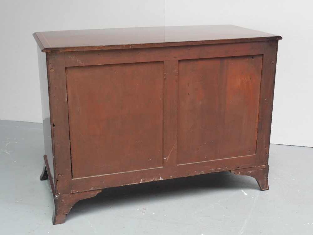 A Georgian flame mahogany bowfront chest of drawers featuring four graduating drawers with brass ring handles and bracket feet. View XII