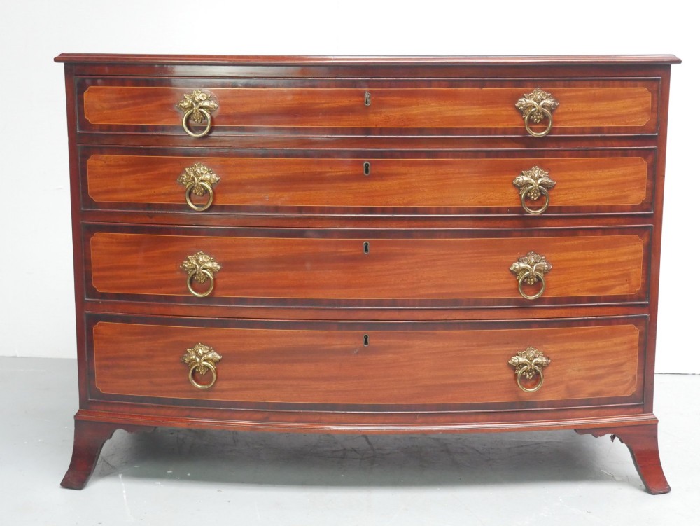 A Georgian flame mahogany bowfront chest of drawers featuring four graduating drawers with brass ring handles and bracket feet. View XV
