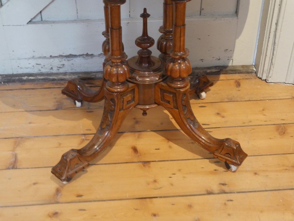 A 19th-century Irish walnut fold-over games table with a scalloped carved apron, turned twin pedestal supports, and carved splayed legs on white castors. View III