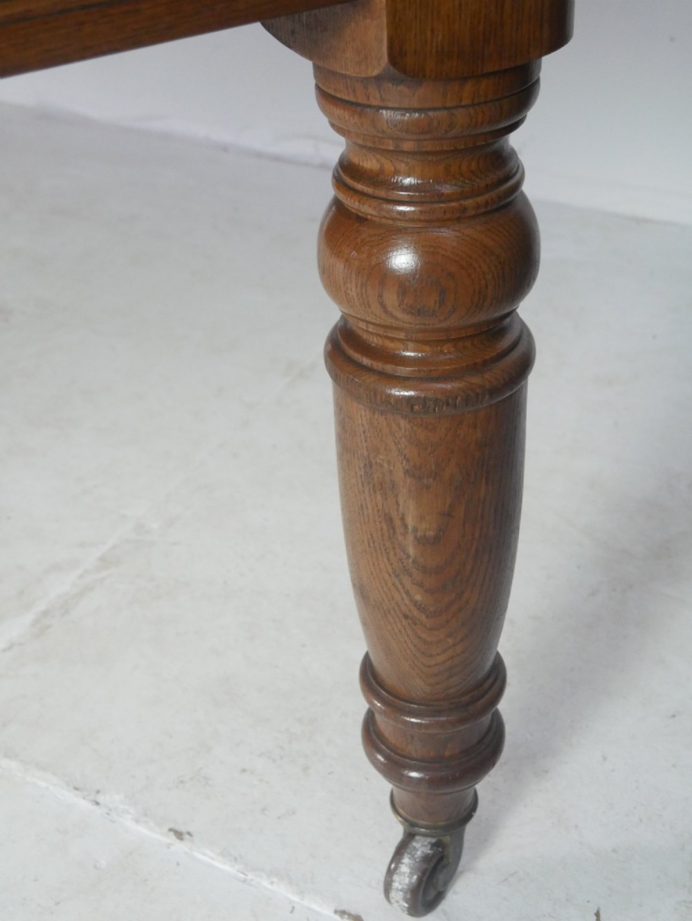 A 19th-century oak extending dining table featuring turned baluster legs set on brass castors with an inserted extension leaf. View III