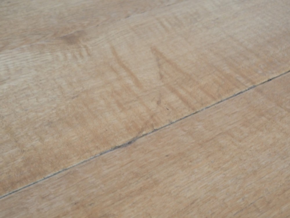 A circular solid oak centre table featuring splayed square legs connected by a central cross-stretcher. View V