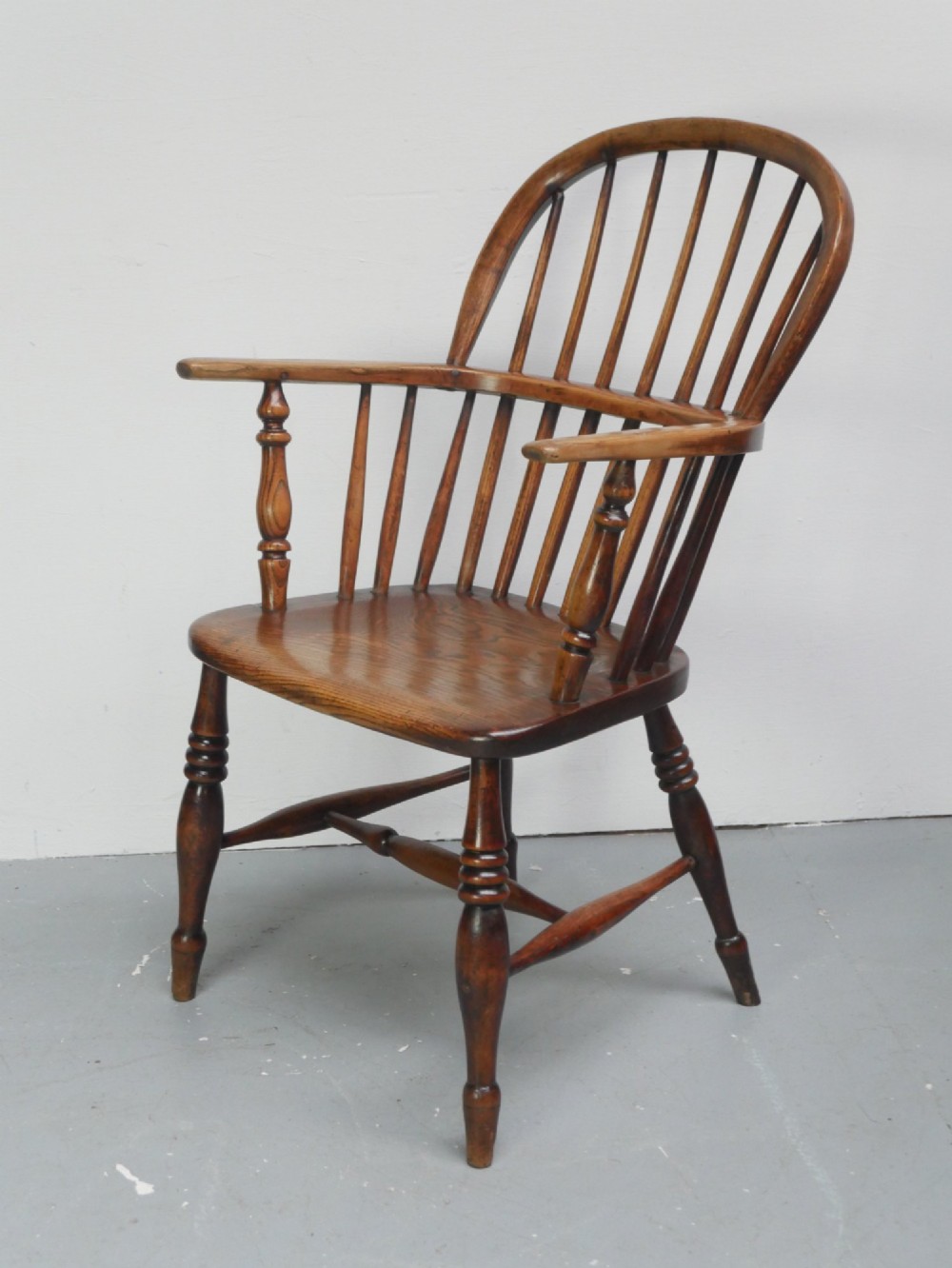 A warm brown wooden Scottish Windsor armchair featuring a hoop back with vertical spindles, shaped saddle seat, and turned legs. View III