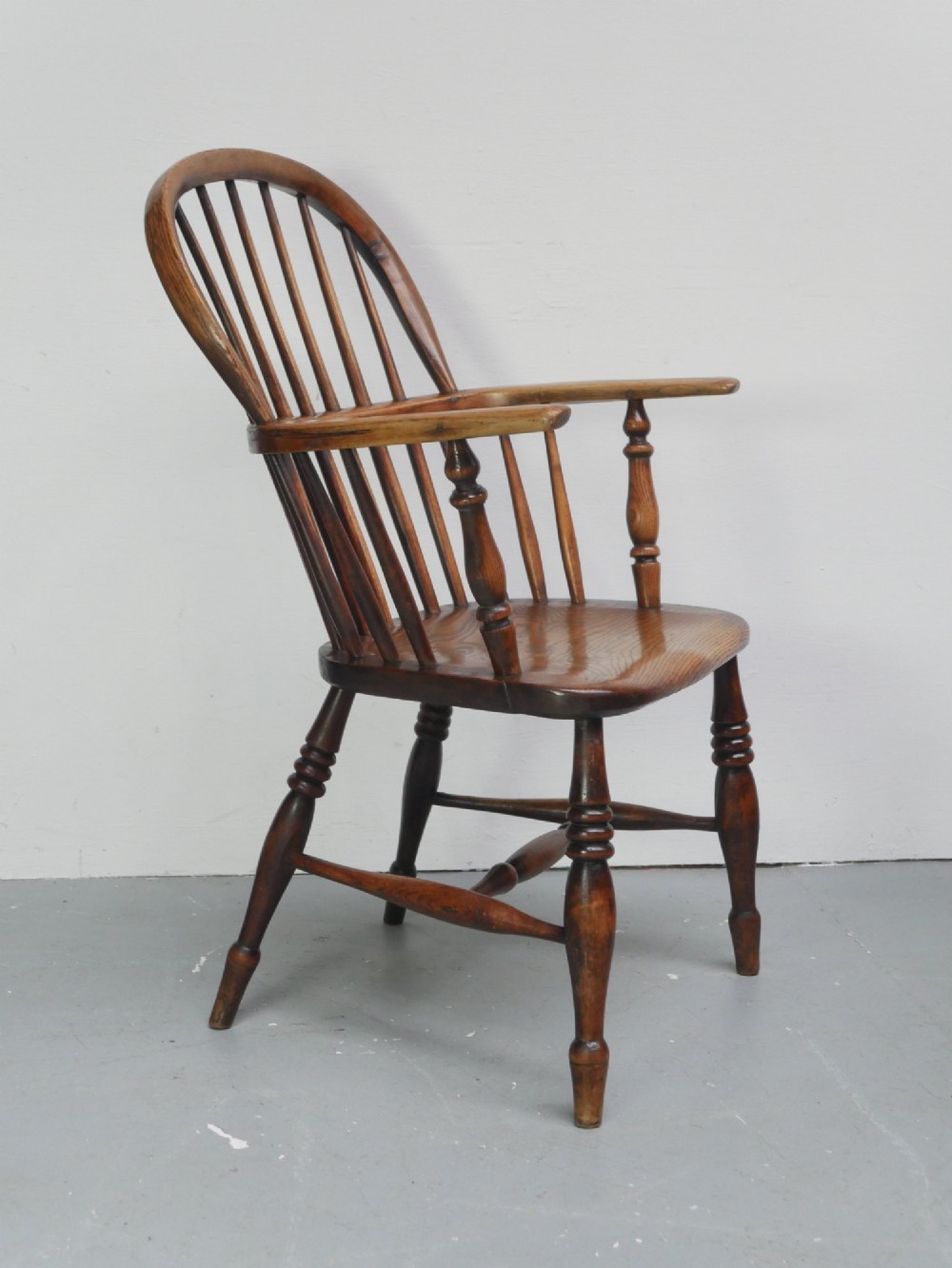A warm brown wooden Scottish Windsor armchair featuring a hoop back with vertical spindles, shaped saddle seat, and turned legs. View IV