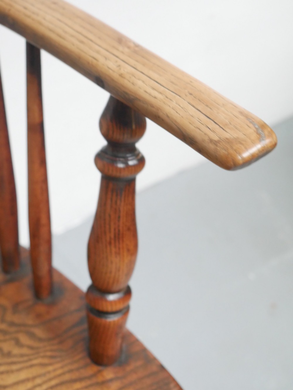 A warm brown wooden Scottish Windsor armchair featuring a hoop back with vertical spindles, shaped saddle seat, and turned legs. View V
