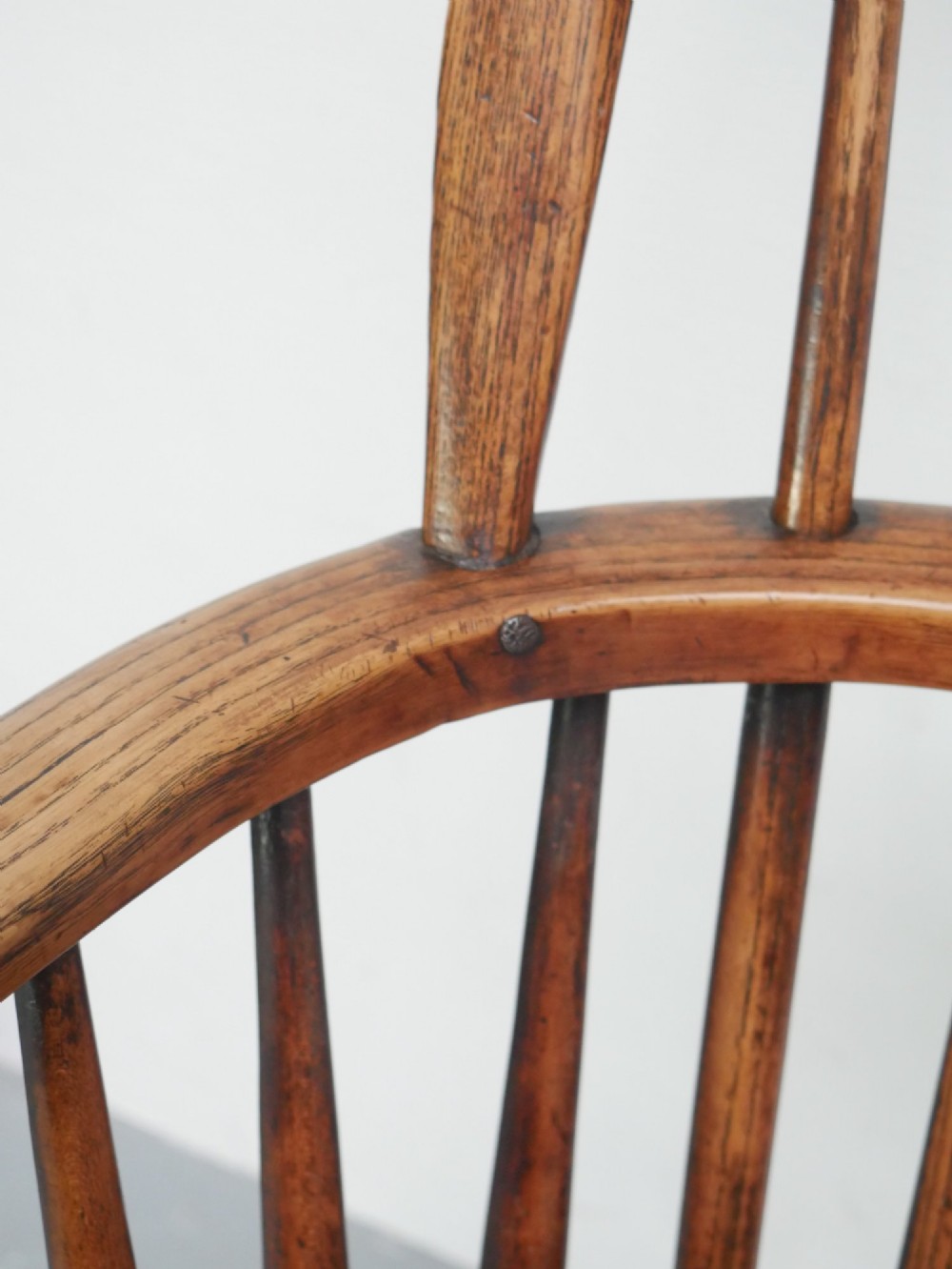 A warm brown wooden Scottish Windsor armchair featuring a hoop back with vertical spindles, shaped saddle seat, and turned legs. View VII