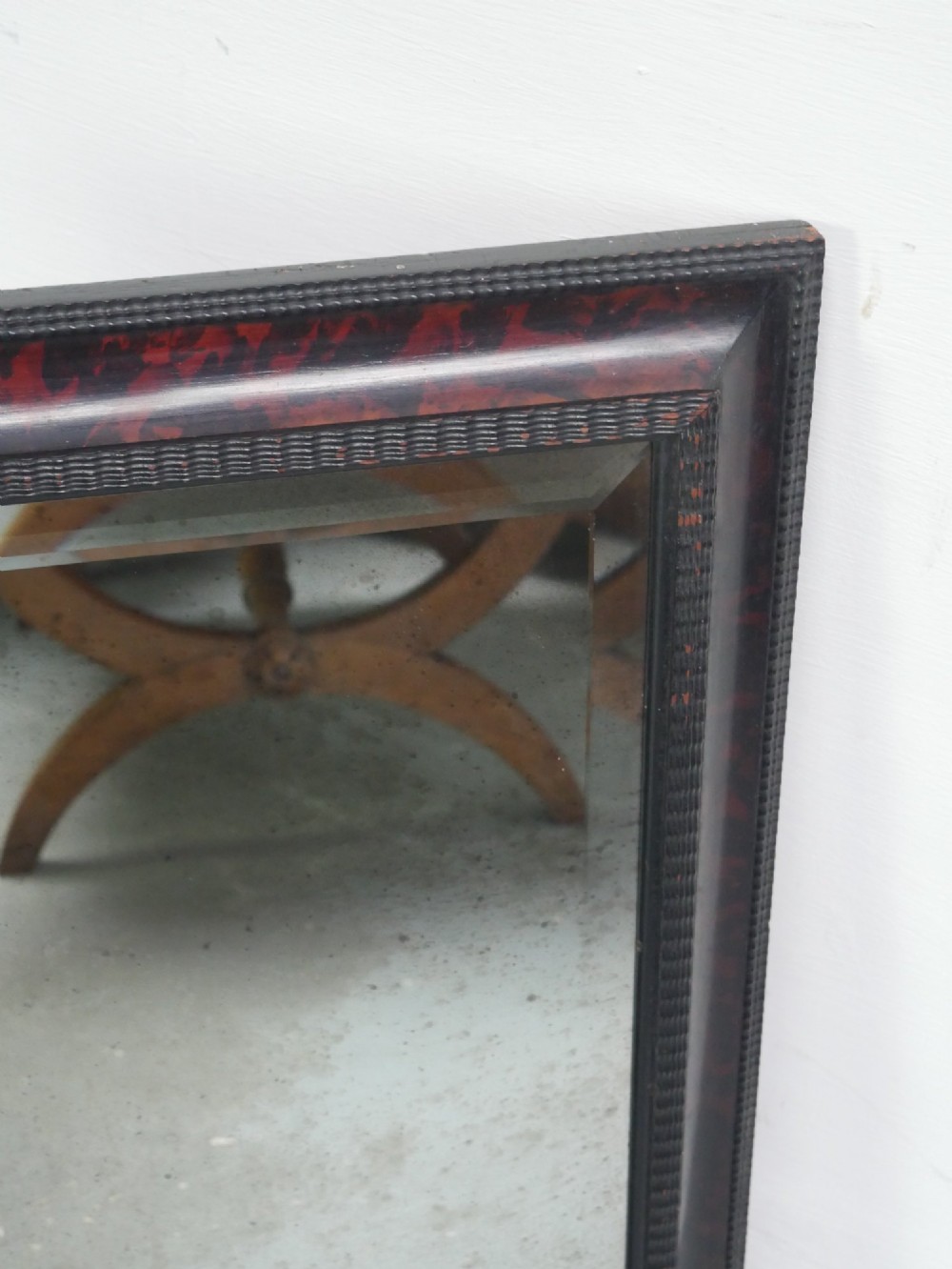 A rectangular wall mirror with a dark red and black mottled faux tortoiseshell frame featuring beaded inner moulding. View III