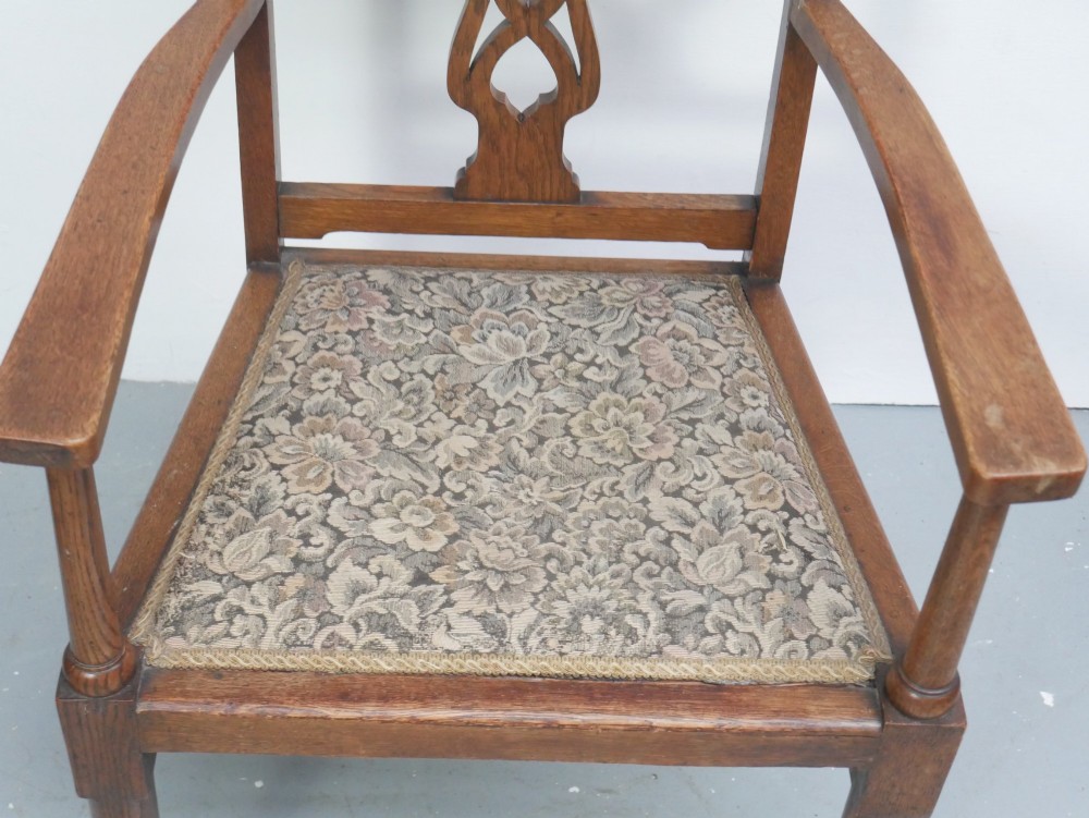 An antique oak armchair featuring a carved top rail, tapestry fabric back panel and seat, and a pierced decorative back splat. View II