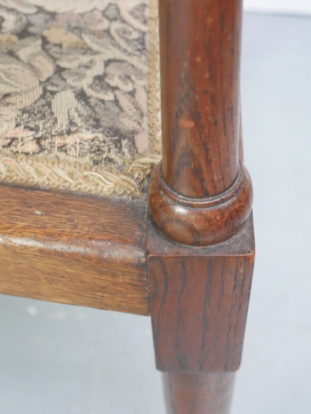 An antique oak armchair featuring a carved top rail, tapestry fabric back panel and seat, and a pierced decorative back splat. View V