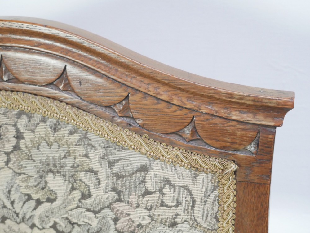An antique oak armchair featuring a carved top rail, tapestry fabric back panel and seat, and a pierced decorative back splat. View VII