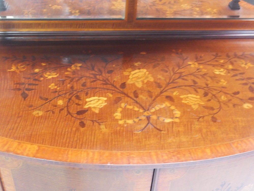 An antique mahogany display cabinet featuring marquetry urn inlays on lower doors, curved bowfront glass doors, glass shelves, and a swan-neck pediment. View II