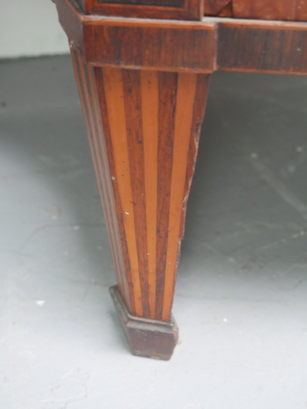 An antique mahogany display cabinet featuring marquetry urn inlays on lower doors, curved bowfront glass doors, glass shelves, and a swan-neck pediment. View IX
