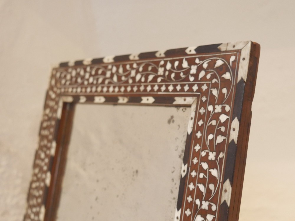 A nineteenth-century rectangular wooden mirror frame with intricate white floral bone inlay patterns surrounding foxed mirror glass. View VI