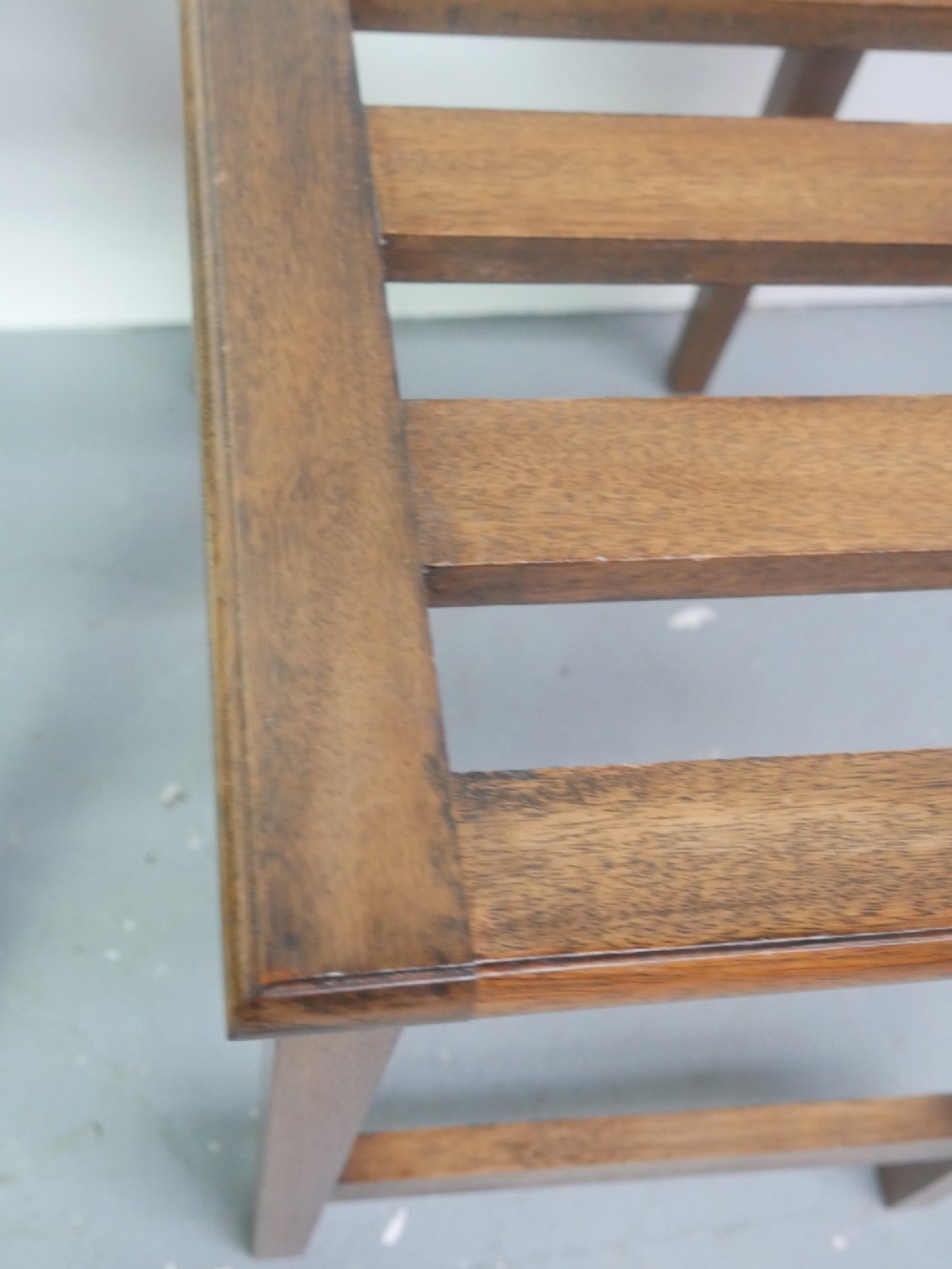 A pair of rectangular warm brown walnut luggage racks featuring slatted tops, straight stretchers, and tapered legs. View VI