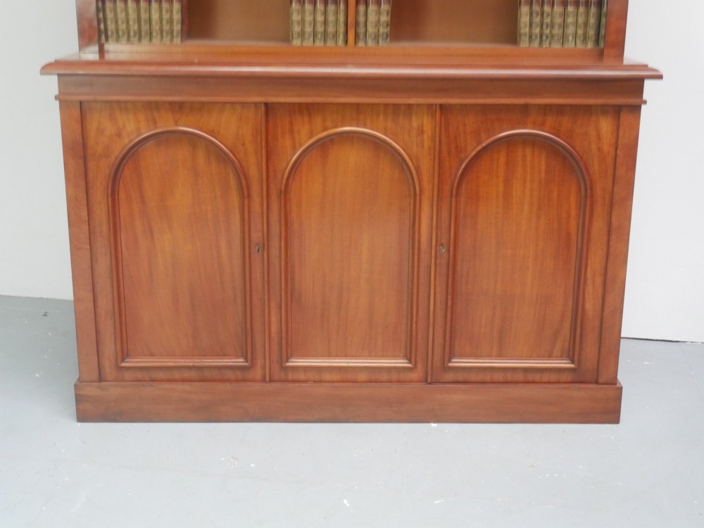 A large nineteenth-century mahogany bookcase featuring open upper shelving and a lower cupboard with three arched panel doors. View II