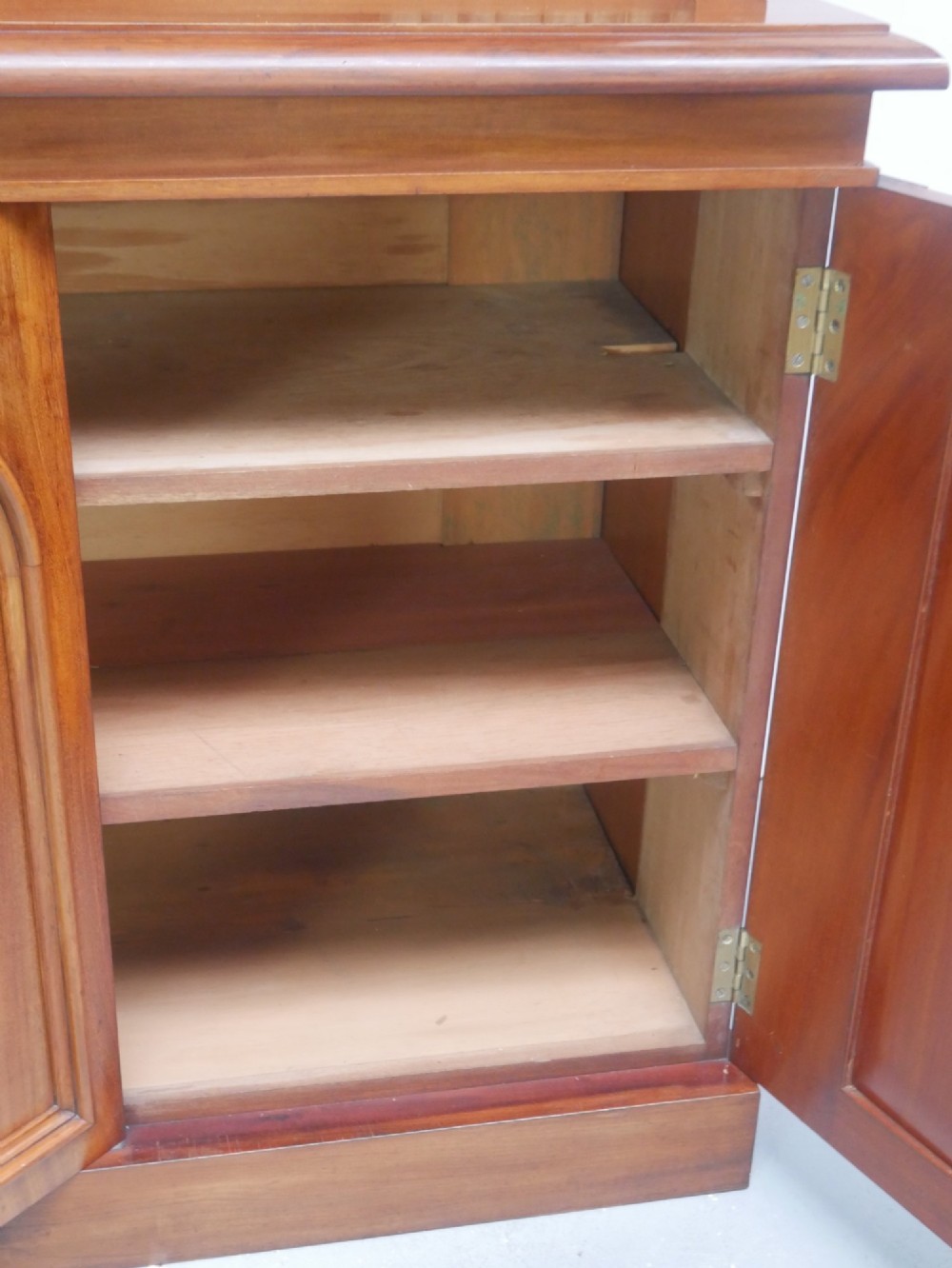 A large nineteenth-century mahogany bookcase featuring open upper shelving and a lower cupboard with three arched panel doors. View IV