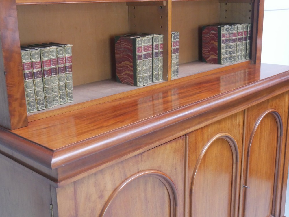 A large nineteenth-century mahogany bookcase featuring open upper shelving and a lower cupboard with three arched panel doors. View V