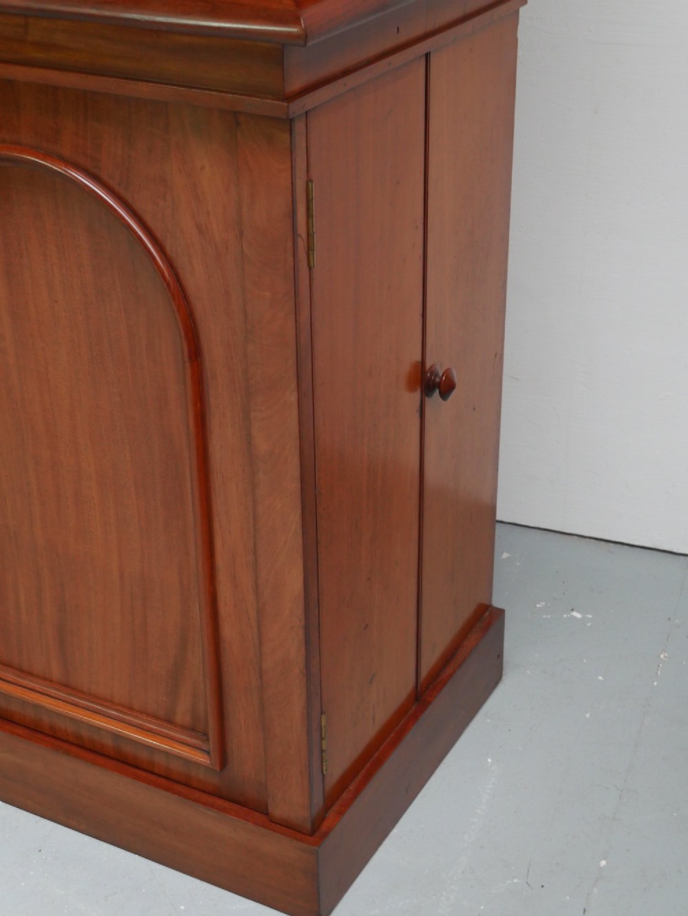 A large nineteenth-century mahogany bookcase featuring open upper shelving and a lower cupboard with three arched panel doors. View XV