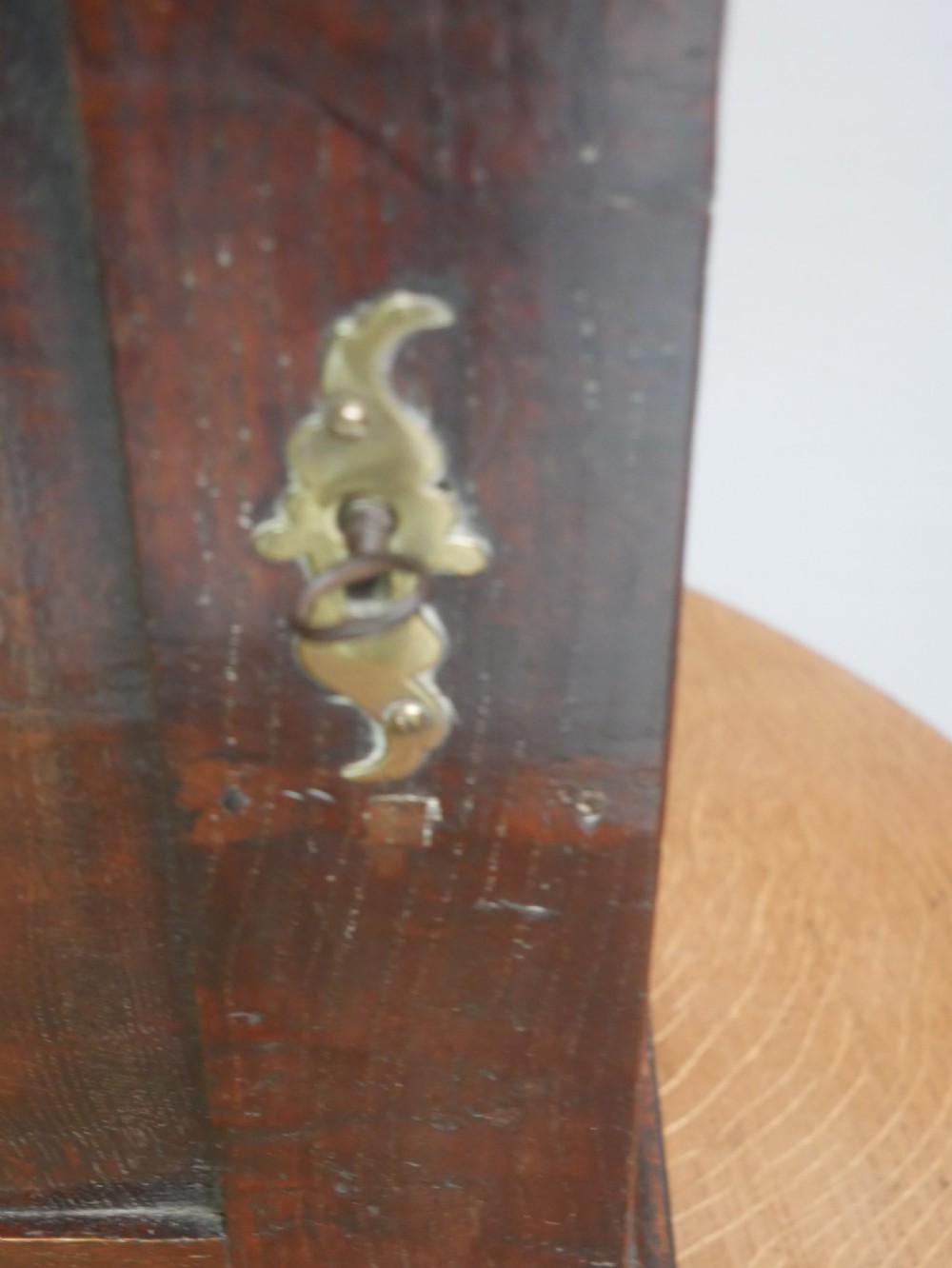 An 18th-century dark oak spice cupboard with a single fielded panel door, brass escutcheon, and bun feet. View V